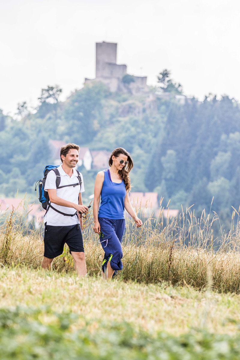 Goldsteig-Wanderer bei Oberviechtach im Oberpfälzer Wald. Im Hintergrund ist die Burg Murach zu sehen